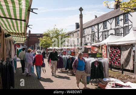 Menschen zu Fuß zwischen den Ständen umliegenden Kriegerdenkmal am Wochenmarkt auf dem Marktplatz in Poulton le Fylde Lancashire England Großbritannien Stockfoto