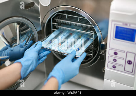 Zahnarzt ist laden Zahnärztliche Sonden in die Maschine sterilisieren Stockfoto