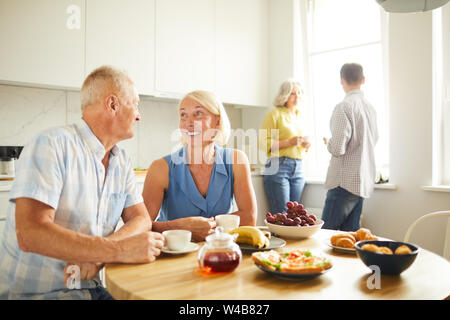 Portrait von Happy reifes Paar an jedem anderen Standort suchen, zärtlich, während am Küchentisch im Sonnenlicht, kopieren Raum Stockfoto