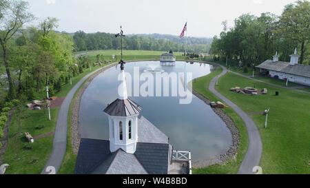 Luftaufnahme von alten, restaurierten Scheunen durch einen Teich an einem Frühlingstag Stockfoto