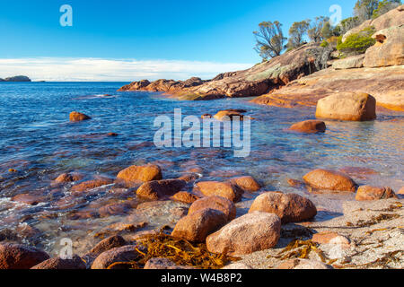 Verschlafenen Bucht im Freycinet National Park, Tasmanien, Australien auf einem blauen Himmel Winter Tag, berühmt für den roten Felsen und große Felsbrocken Stockfoto