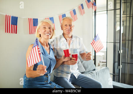 Portrait von fröhlichen senior Paar wehende Amerikanische Flagge und lächelnd an Kamera, kopieren Raum Stockfoto
