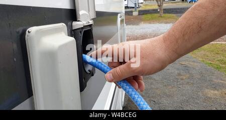 Nahaufnahme der Hand halten Wasser Schlauch Wasserbehälter in Reisemobil zu füllen Stockfoto