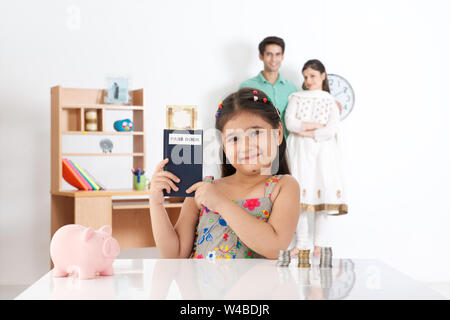 Mädchen zeigt Bankbuch mit ihren Eltern im Hintergrund Stockfoto