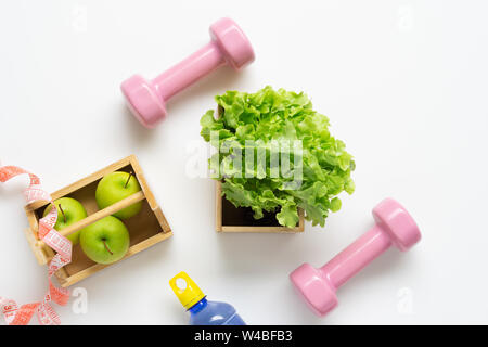 Flach Training und Fitness Diät gesunde Lebensweise mit gesunden Lebensmitteln grüne Äpfel und grünen Salat, rosa Kurzhanteln, eine Flasche Wasser und Messen ta Stockfoto