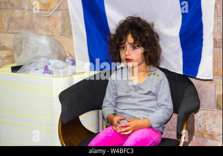 5. Mai 2018 ein hübsches junges jüdisches Mädchen sitzt ruhig vor einem israelischen Flagge als ihre Eltern an Kunden in Ihrem Restaurant in Nazaret besuchen Stockfoto