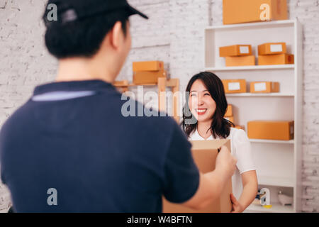 Junge glücklich und lächelnd Asiatischen nach Business Frauen im Büro erhält ein Paket von männlichen deliverman-online Kauf und Versand Konzept Stockfoto