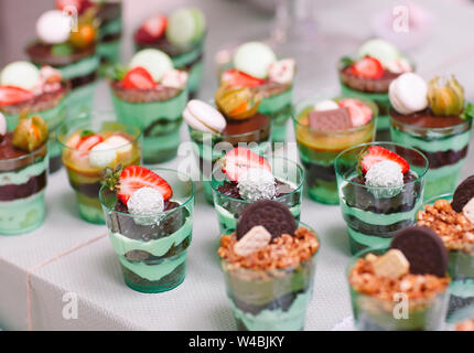 Kleinigkeiten in Kunststoff Gläser mit frischem Obst und Sahne. Stockfoto