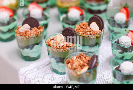 Kleinigkeiten in Kunststoff Gläser mit frischem Obst und Sahne. Stockfoto