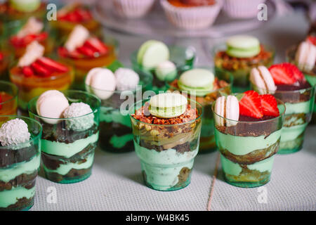 Kleinigkeiten in Kunststoff Gläser mit frischem Obst und Sahne. Stockfoto