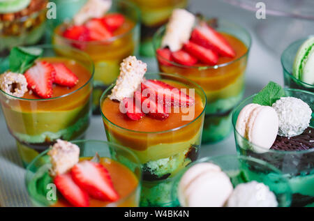 Kleinigkeiten in Kunststoff Gläser mit frischem Obst und Sahne. Stockfoto