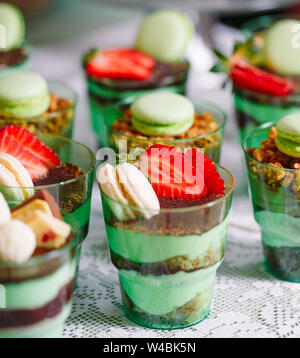 Kleinigkeiten in Kunststoff Gläser mit frischem Obst und Sahne. Stockfoto