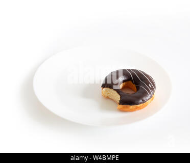 Essen Schokolade Donut auf weißem Hintergrund. Donut auf einem weißen Teller gebissen worden Stockfoto