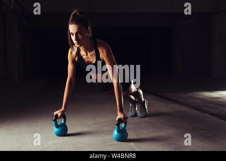 Schlanke Brünette, Push-ups Übungen auf Kettlebells Stockfoto