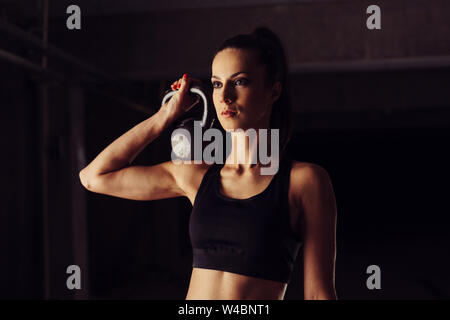 Attraktive junge Frau mit kettlebell auf ihrer Schulter Stockfoto