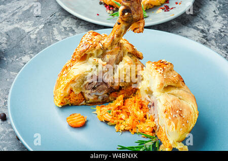 Hähnchenschenkel in Blätterteig. Hühnerbein in Blätterteig gebackenes Huhn auf dem Tisch. Stockfoto