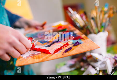 Farbe auf der Palette. Schöne Mädchen in ein Gemälde Studio zeichnet ein Bild. Stockfoto