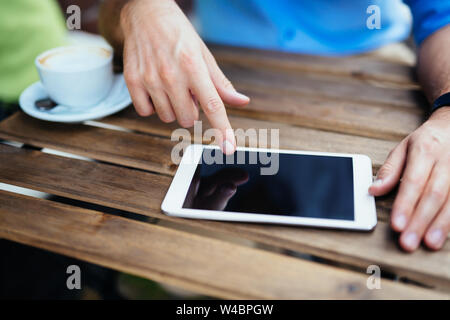 Nahaufnahme der männlichen Händen mit einem digitalen Tablet an einem Tisch im Freien Stockfoto
