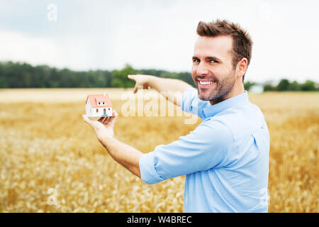 Glückliche Menschen, die sich auf Feld für neues Haus Stockfoto