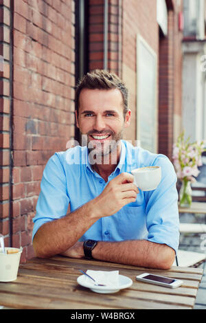 Senkrechte Aufnahme von gutaussehenden jungen Mann trinken Kaffee im Cafe sitzen im Freien Stockfoto