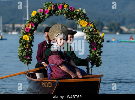 Radolfzell, Deutschland. 22. Juli, 2019. Träger von traditionellen Kostümen auf einem Boot mit Kränze mit Blumen geschmückt in den Hafen von Radolfzell am Bodensee während der Moos wasser Prozession. Die Prozession wurde in 1926 das erste Mal auf dem Wasser über den Bodensee. Es geht zurück bis in das 18. Jahrhundert. 1796 Die Bürger von Moos eine rinderseuche - aus Dankbarkeit für diese verschont blieben, die Veranstaltung findet jedes Jahr am dritten Montag im Juli. Quelle: Patrick Seeger/dpa/Alamy leben Nachrichten Stockfoto