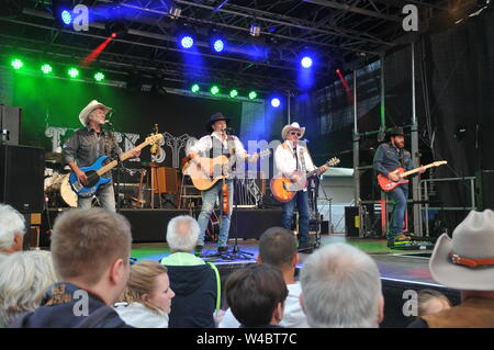 16 Juli 2019, Schleswig-Holstein, Heiligenhafen: TRUCK STOP - Country Band von waterkant am 16. Juli 2019 in Heiligenhafen am Heiligenhafener Hafenfesttage (für den 44. Von 11. Juli bis 21. Juli 2019) open air Bühne dierkt am Hafenbecken. Von 20 - 22 Uhr gab es Country Rock und Songs aus dem neuen Album 'Ein Stückchen Ewigkeit' über zweitausend Gäste der Veranstaltung. Schleswig-Holstein, Deutschland, Europa. Auf der Bühne - von links vorne. Uwe verloren, Tim Reese, Andreas Cisek und Chris Kaufmann. Zurück links Teddy Ibing - Schlagzeug und Recht, Knut Bewersdorff - s Stockfoto