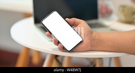 Der Mann mit der rechten Hand Smartphone mit leerer Bildschirm in seinem Büro Stockfoto