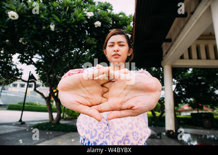 Asiatische Frau mit geschlossenen Augen tun Aufwärmen Übung für Arme während Outdoor Training im City Park Stockfoto