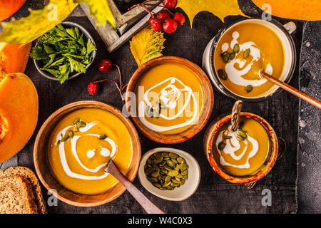 Herbst Kürbis Suppe pürieren, mit Sahne in cups, dem Herbst Landschaft. Gesunde vegane Ernährung Konzept. Herbst essen Konzept. Stockfoto