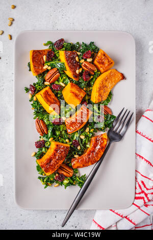 Kürbis Salat mit Nüssen, Preiselbeeren und Kale in rechteckigen Platte. Stockfoto