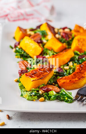 Kürbis Salat mit Nüssen, Preiselbeeren und Kale in rechteckigen Platte. Stockfoto