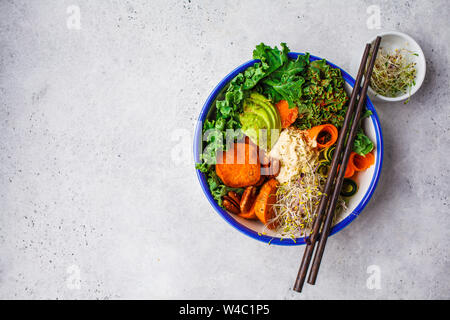 Gesund vegan Mittagessen in einer weißen Schüssel. Buddha Schüssel mit Avocados, süsse Kartoffeln, Rosenkohl und Gemüse. Stockfoto