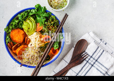 Gesund vegan Mittagessen in einer weißen Schüssel. Buddha Schüssel mit Avocados, süsse Kartoffeln, Rosenkohl und Gemüse. Stockfoto