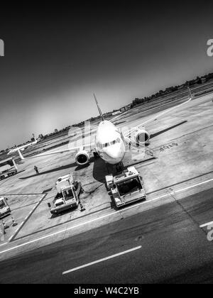 Künstlerische schwarz-weiß Foto oder ein Foto von einem Flughafen Flugzeug für den Start vorbereitet wird. Stationäre Flugzeuge mit Menschen laden seiner Kraftstofftank und Stockfoto