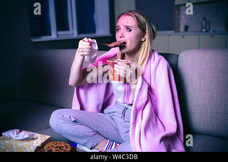 Junge Frau ansehen Film in der Nacht. Trauriges Bild von Modell sitzen auf dem Sofa und weinte. Eis essen. Gerade traurig TV-Serie und Film. Allein in roo Stockfoto