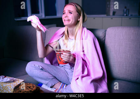 Junge Frau ansehen Film in der Nacht. Emotionale Modell sitzen auf dem Sofa und weinte. Sie traurigen Film oder TV-Serien. Allein im dunklen Zimmer Stockfoto