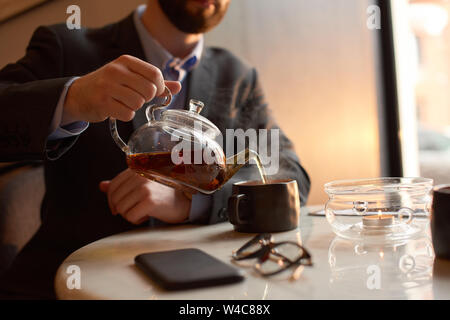 Nahaufnahme eines Ma im Anzug gießt Kaffee in eine Tasse. Stockfoto