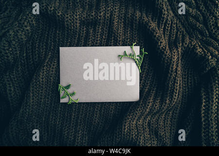 Leeres Blatt auf einen warmen Pullover. Gemütliche Herbst oder Winter Mockup für Text. Flach, Ansicht von oben. Stockfoto