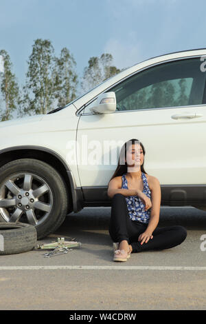 Frau wartet auf der Straße neben einem kaputten Auto Stockfoto