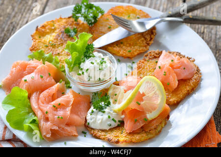 Knusprige Kartoffelpuffer mit Räucherlachs und saure Sahne mit frischen, grünen Kräutern Stockfoto