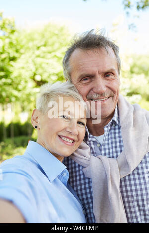 Portrait von liebevollen senior Paar lächelnd von der Kamera im Freien, während für selfie Foto posiert Stockfoto