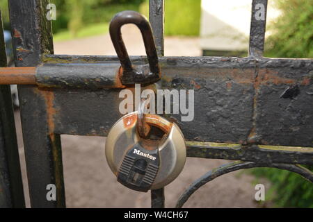 Kreisförmige Master Security Lock auf schwarz lackiert Rost schmiedeeisernen Zaun mit öffnen Sie die Verriegelung wieder Home Haus Sicherheit Stockfoto