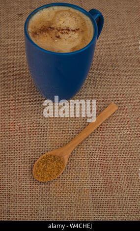 Blaue Tasse Kaffee mit Milch und Zimt mit hölzernen Löffel gefüllt mit Rohrzucker Stockfoto