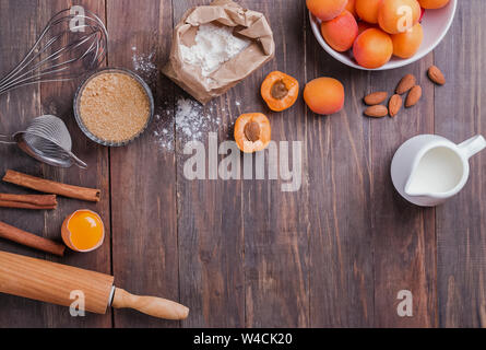 Bestandteile und Elemente für eine Torte mit Aprikosen auf dem hölzernen Hintergrund, Ansicht von oben Stockfoto
