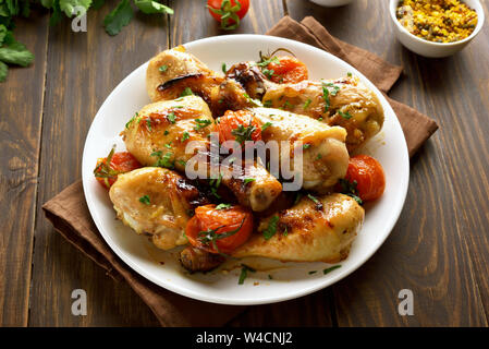 Gegrilltes Hähnchen drumstick und gerösteten Tomaten auf weiße Platte Stockfoto