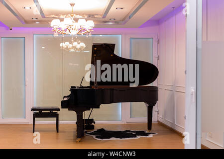 Luxuriöses Musikzimmer mit Flügel und Kronleuchter mit bunter Beleuchtung. Stockfoto