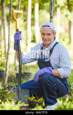 Volle Länge Portrait von reifer Mann im Garten arbeiten und Suchen an Kamera Stockfoto