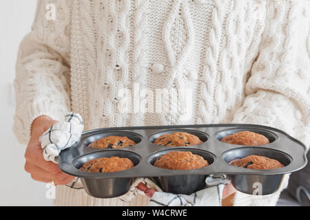 Womas Hände halten ein Fach mit leckeren frisch gebackene Muffins close-up Stockfoto