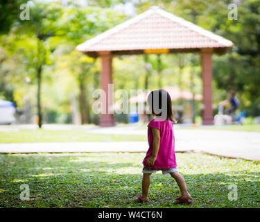 Asiatische kleinkind Mädchen im Park läuft von hinten im Frühjahr oder Sommer. Stockfoto