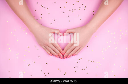 Woman's Hand mit rosa Maniküre Herz. Stockfoto